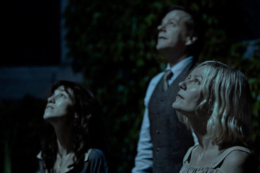 trois personnes sont dehors dans la nuit et regardent le ciel.