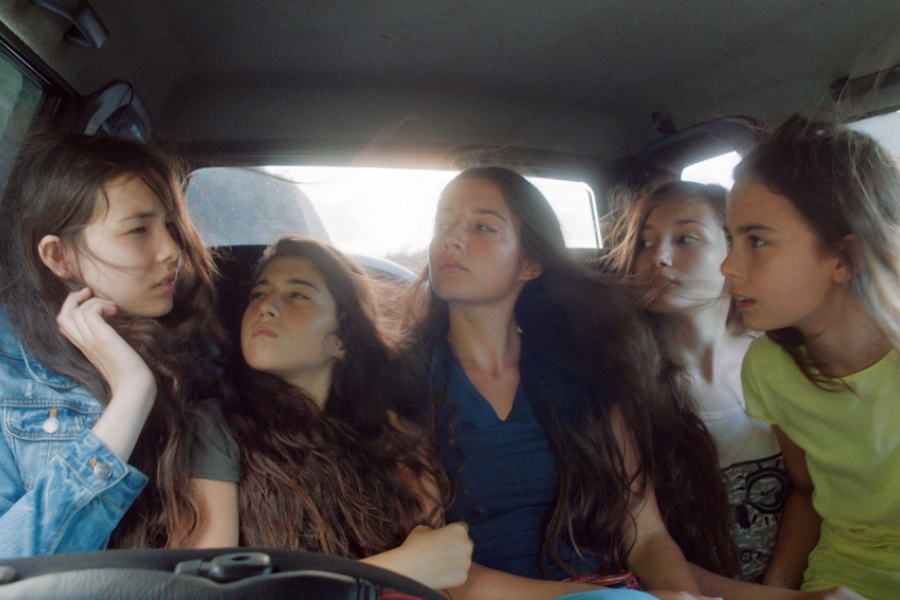 Les cinq soeurs sont à l'arrière d'u véhicule. 