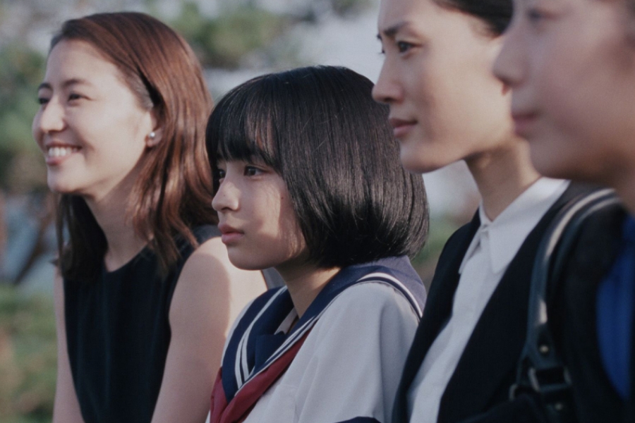 Les trois grandes soeurs sont autour de la nouvelle petite soeur, qui est habillée en écolière