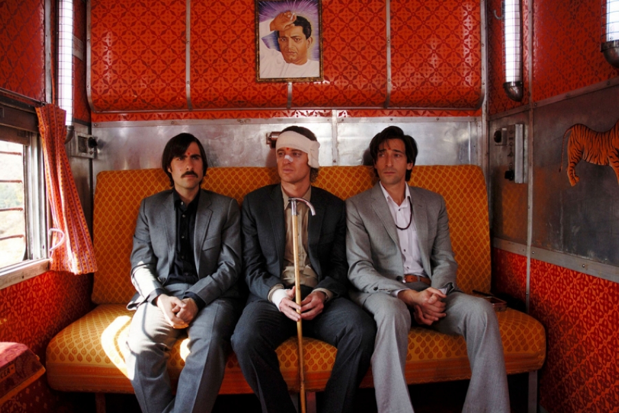 Les trois frères sont dans le Darjeeling, un train en Inde. Ils sont assis dans une cabine orange. Celui qui est au milieu porte des bandages sur la tête et le visage. Les trois portent des costumes.