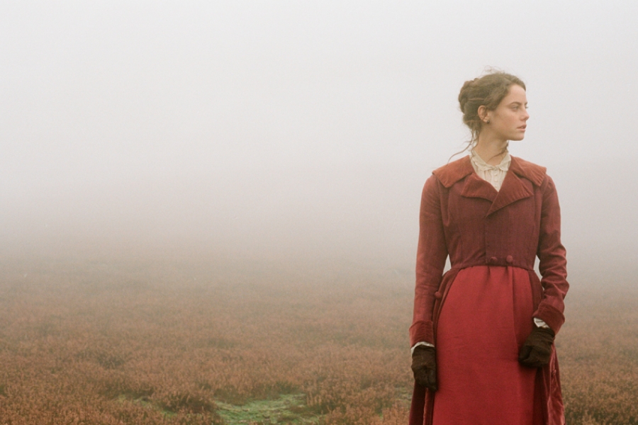 Dans la nature, cachée par une brume épaisse, on distingue une jeune femme en robe rouge.