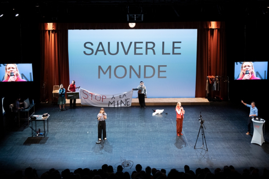 6 acteurs et actrices sont sur scène, un grand écran affichant "sauver le monde" derrière eux. Ils animent un débat 
