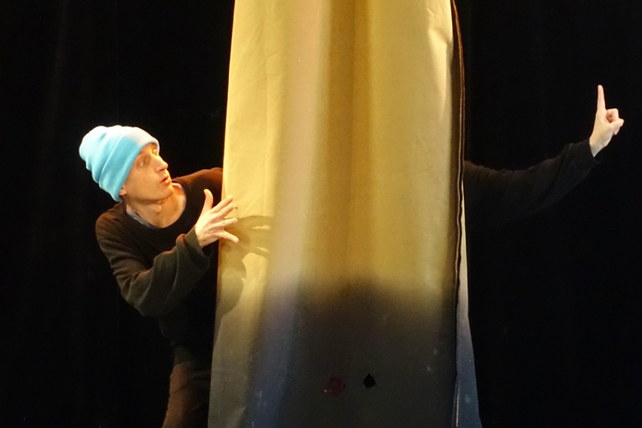 Un danseur joue avec un tissus jaune qui descend du plafond 