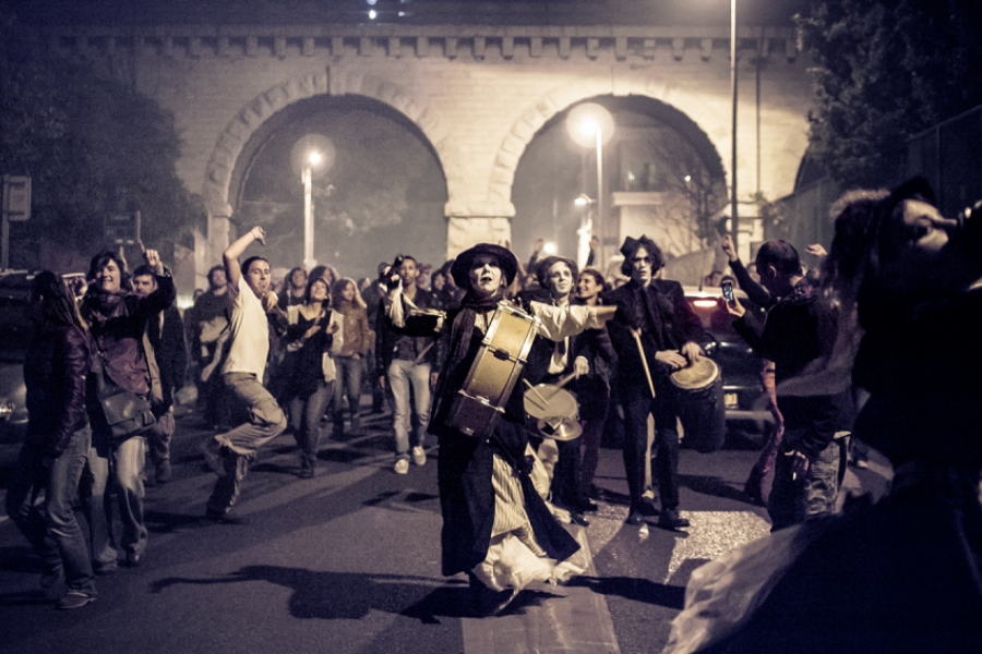 Des musiciens habillés en morts-vivants déambulent avec des passants dans une rue 