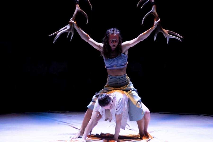 Une danseuse tient des bois de cerf dans ses mains au dessus d'une autre danseuse