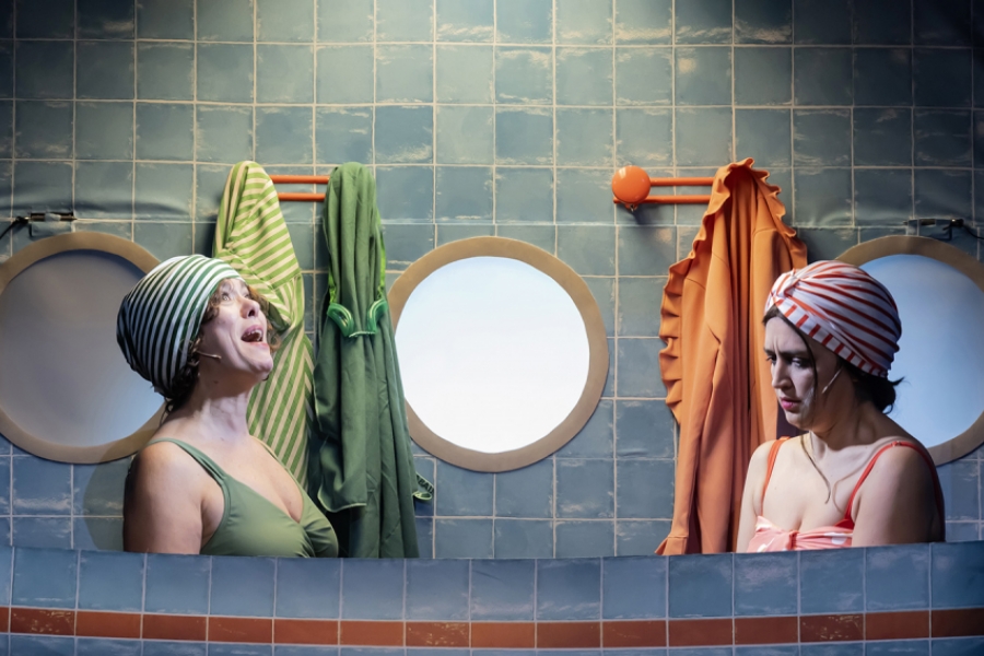 2 comédiennes sont en maillot de bain et bonnet de bain dans une salle de bain