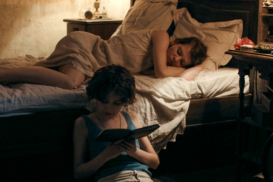 Femme au lit, son fils à terre lit une histoire