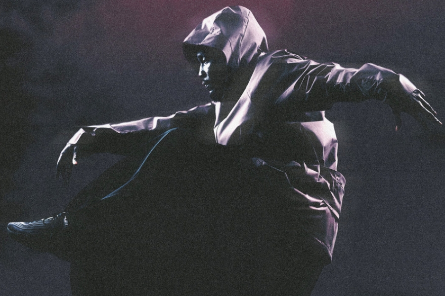Un danseur habillé de noir danse au sol 