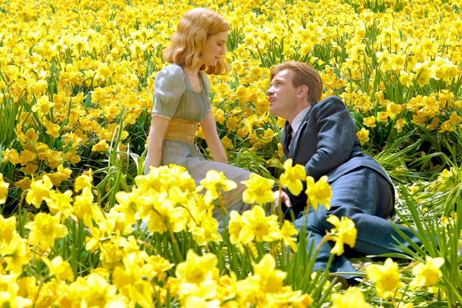 1 homme allongé aux genoux d'une femme, entourés de jonquilles