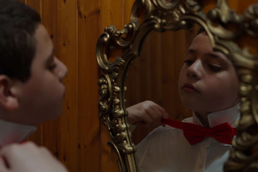 Enfant en train de faire son nœud papillon devant le miroir