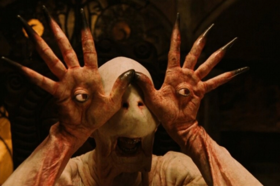 Un alien met ses mains devant lui, à l'intérieur, des yeux