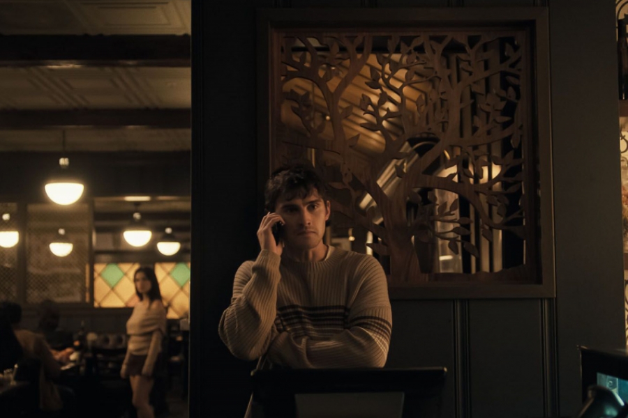Homme au bar au téléphone, femme en arrière-plan qui l'observe