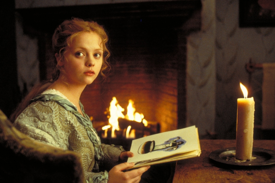 Femme à côté d'une cheminée, livre à la main